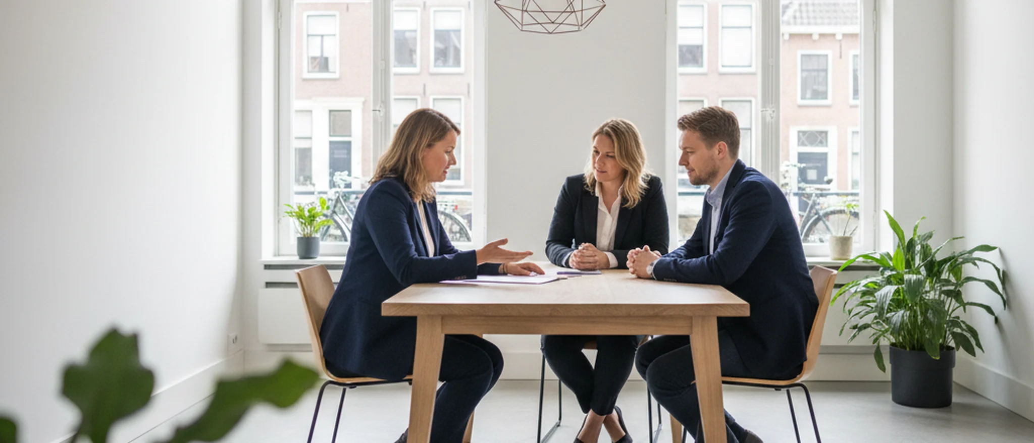 Mediator bespreekt scheidingsdocumenten met een stel in een modern Nederlands kantoor