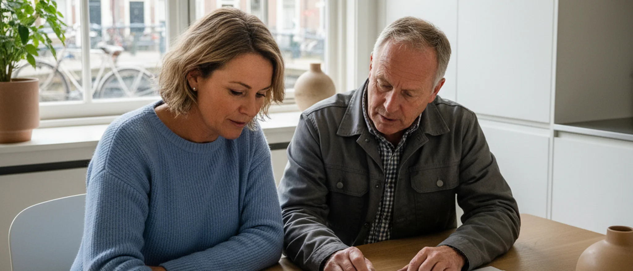 Huiseigenaar en klusjesman bekijken samen een offerte aan de keukentafel